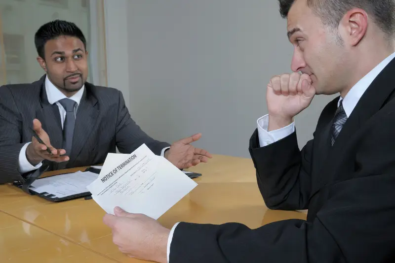 Person packing belongings at their desk after unexpected termination, questioning workplace rights